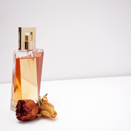 parfum avec une fleur séchée sur fond blanc